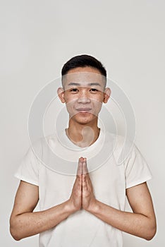 Portrait of young asian man with problematic skin and hyperpigmentation on his face looking at camera, folding hands