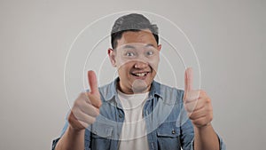 Portrait of young Asian man shows thumbs up sign, happy smiling person, OK deal