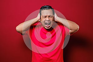 Portrait of young Asian man wearing casual red shirt closing his eyeas and ears dont want or avoiding to hear bad news, stress