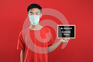 Portrait of  young Asian man wearing protective mask, holding small blackboard written