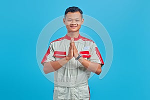 Portrait of young asian mechanic greeting with big smile on his face over blue background
