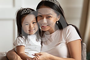 Portrait of young Asian mom and daughter posing at home