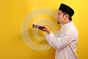 Portrait of young Asian Muslim man look at the light when the Holy Quran opened