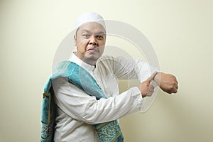Portrait of young Asian muslim man pointing at his wristwatch