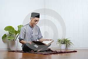 Portrait of Young Asian Muslim man reading holy Qur`an on Ramadan Kareem