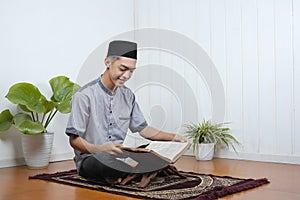 Portrait of Young Asian Muslim man reading holy Qur`an on Ramadan Kareem