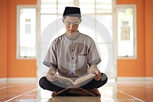 Portrait of Young Asian Muslim man reading holy Qur`an on Ramadan Kareem