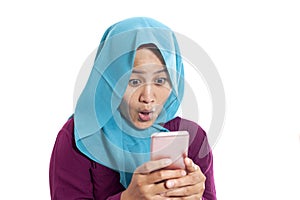 Portrait of young Asian muslim woman get good news on her phone, happy surprised expression