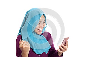 Portrait of young Asian muslim woman get good news on her phone, happy surprised expression