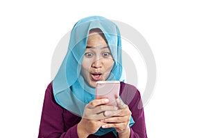 Portrait of young Asian muslim woman get good news on her phone, happy surprised expression