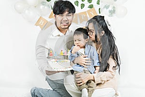 Portrait of young asian parents keep in arms, hugging child kid baby boy,celebrating birthday holiday party on a minimal