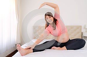 Portrait young asian pregnant female working out at home Pregnant woman practicing yoga at home