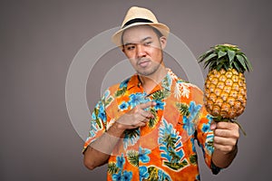 Portrait of young Asian tourist man holding pineapple