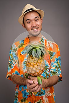 Portrait of young Asian tourist man holding pineapple