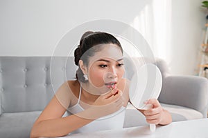 Portrait of Young Asian woman applying lipstick looking at mirror