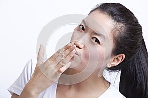 Portrait of young Asian woman blowing kiss against white background