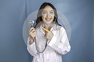 Portrait of a young Asian woman doctor, a medical professional is smiling and wearing stethoscope isolated over blue background