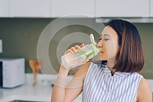 Portrait of young Asian woman drinking detox drink in the kitchen. Healthy concept, weight loss food concept