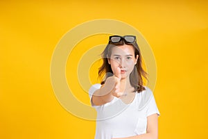 Portrait young asian woman gun shot hand gesture emotion killing business in white t-shirt, Yellow background isolated studio shot