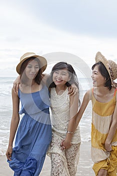 portrait of young asian woman with happiness emotion wearing beautiful dress walking on sea beach and laughing