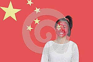 Portrait of young Asian woman with painted face smiling against Chinese flag