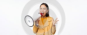 Portrait of young asian woman protester, screaming in megaphone and protesting, standing confident against white