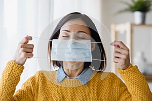 Portrait of young Asian woman,  putting on a medical surgical disposabhttpsle face mask to prevent infection