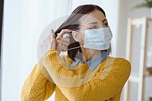 Portrait of young Asian woman,  putting on a medical surgical disposabhttpsle face mask to prevent infection