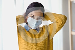 Portrait of young Asian woman,  putting on a medical surgical disposabhttpsle face mask to prevent infection