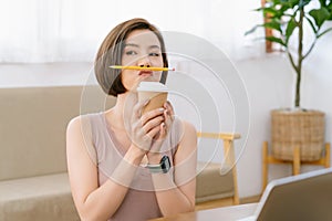 Portrait of young Asian woman rest relax during work keeping pencil between nose and lips as moustache looking funny and naughty
