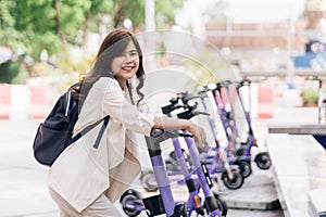 portrait of young asian woman riding electric scooter in park