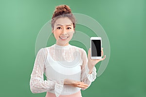 Portrait of young Asian woman showing her blank sreen mobile phone. Isolated over green background