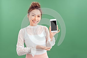 Portrait of young Asian woman showing her blank sreen mobile phone. Isolated over green background