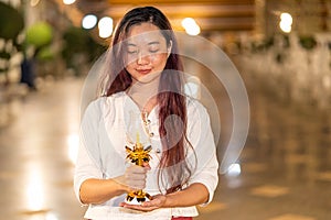 portrait young asian woman is smileing and wearing traditional dress of Thailand holding candle and praying at Wat Suthat