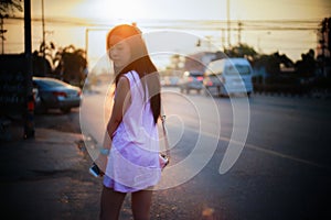 Portrait of young asian woman standing side of street at sunset moment,filtered image,soft focus