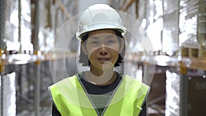 Portrait of young asian woman standing at warehouse, looking at camera and smiling.
