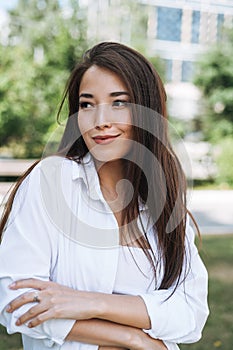 Portrait of young asian woman student with long hair in city park