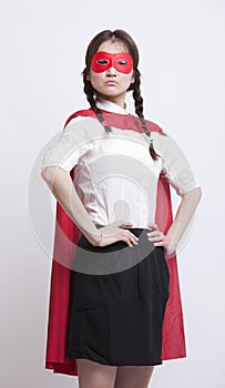 Portrait of young Asian woman in superhero costume with hands on hips against white background