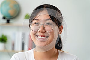 A portrait of young Asian woman wearing eyeglasses, smiling and looking at the camera