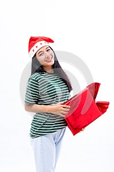 Portrait of a young Asian woman wearing a santa hat and wearing casual clothes carrying a red gift