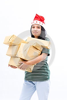 Portrait of a young Asian woman wearing a santa hat and wearing casual clothes lifting a pile of gifts