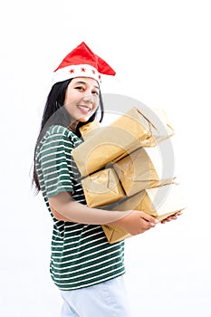 Portrait of a young Asian woman wearing a santa hat and wearing casual clothes lifting a pile of gifts
