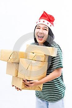 Portrait of a young Asian woman wearing a santa hat and wearing casual clothes lifting a pile of gifts with surprise face