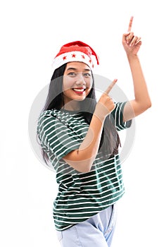 Portrait of young Asian woman wearing a Santa hat and wearing casual clothes pointing towards the copy space above