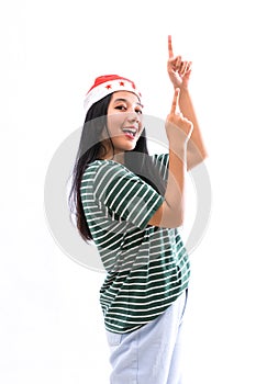 Portrait of young Asian woman wearing a Santa hat and wearing casual clothes pointing towards the copy space above