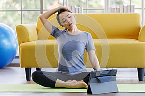 Portrait of young  Asian woman wearing sportswear sitting and looking on a computer screen doing stretching after exercise. Health