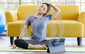 Portrait of young  Asian woman wearing sportswear sitting and looking on a computer screen doing stretching after exercise. Health