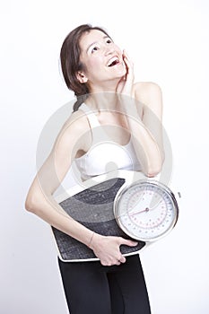 Portrait of young Asian woman with weight scale against white background