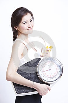 Portrait of young Asian woman with weight scale against white background