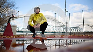 Portrait of young athlete man in windbreaker preparing to exercise